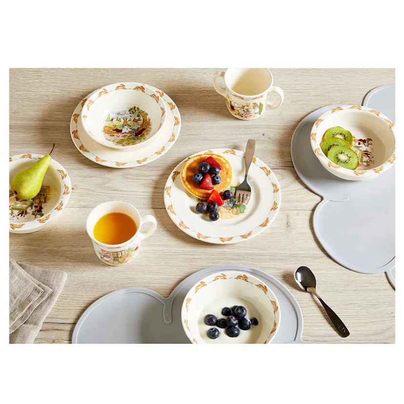 Table setting with ceramic plates, bowls, and cups featuring floral patterns on a wooden table.
