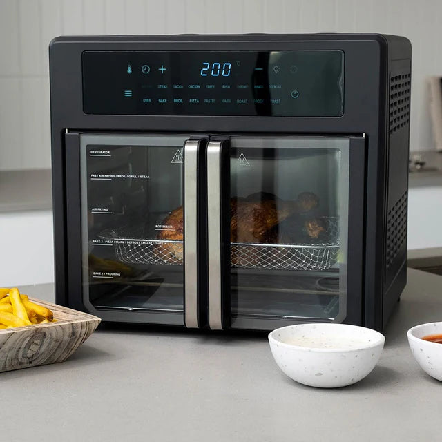 Black toaster oven with digital display on a kitchen counter with food items around