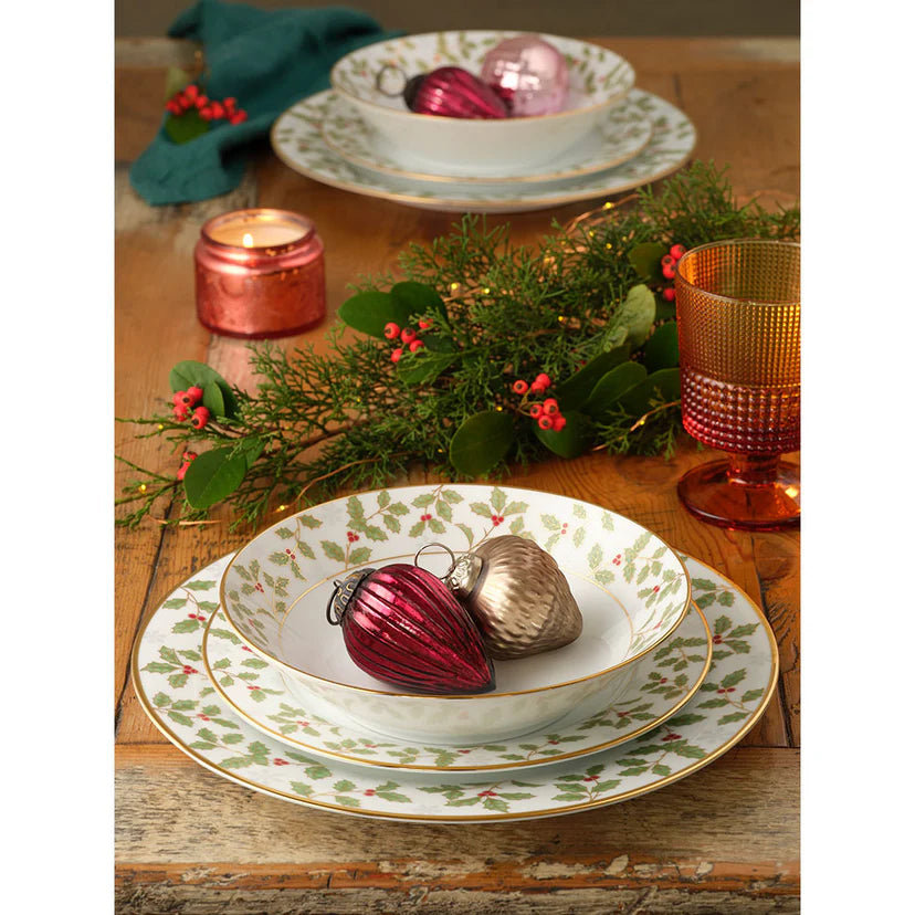 Christmas-themed table setting with decorative ornaments and candles on a wooden table.