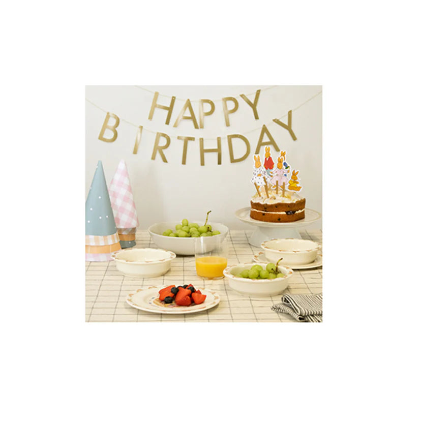 Birthday celebration with cake, balloons, and fruit on a table.