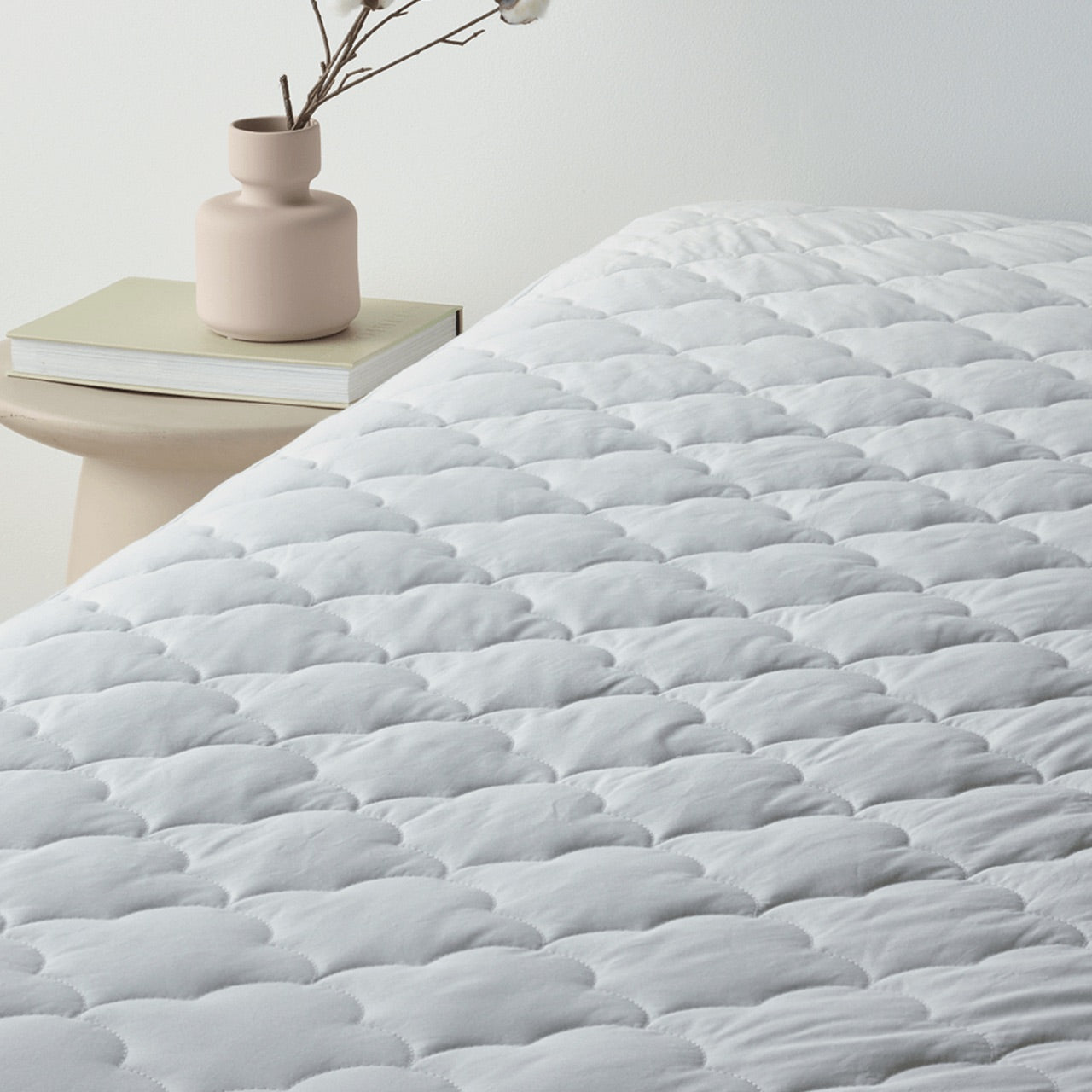 Angled view of Bamboo Wool Mattress Protector on bed