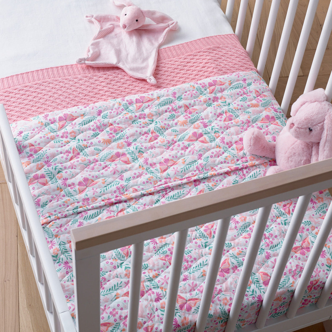 Botanical Cot Comforter on bed with Rattle and Soft Toy
