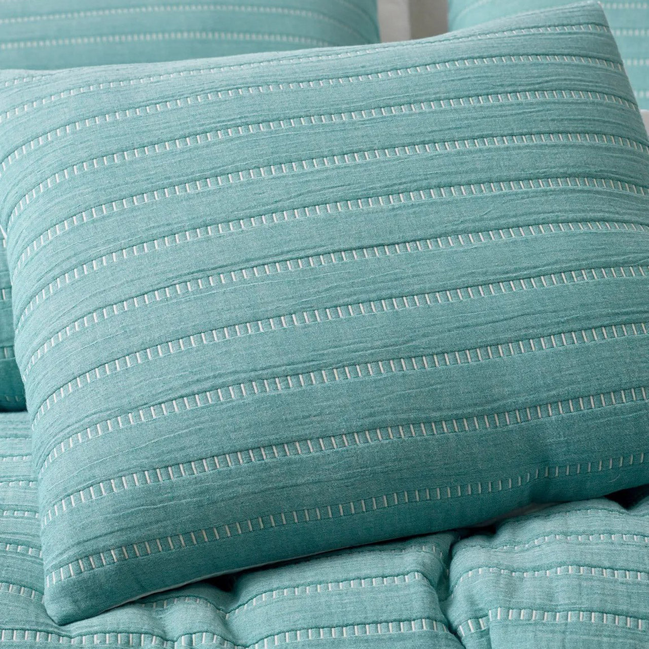 Close up shot of Broadbeach Cushion Cover on bed