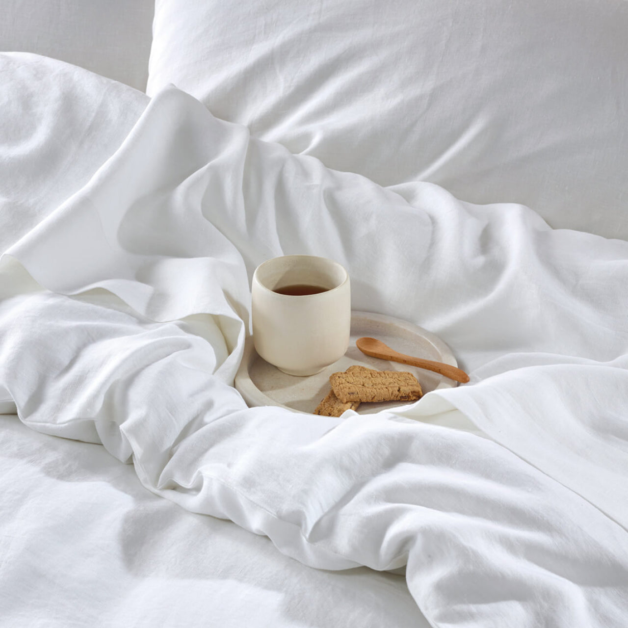 Close up shot of Elayna Quilt Cover White on bed with coffee and biscuits