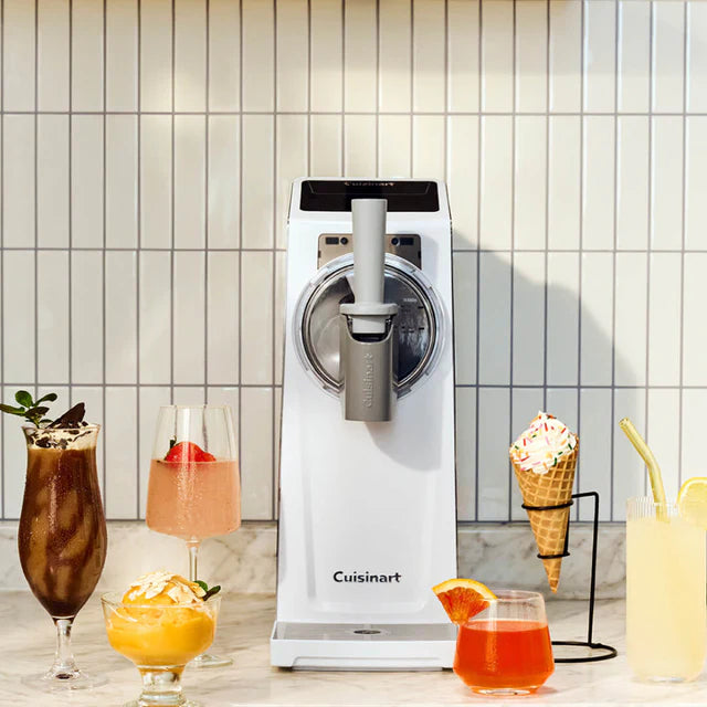 Cuisinart ice cream maker with various ice cream and drink items on a tiled wall background