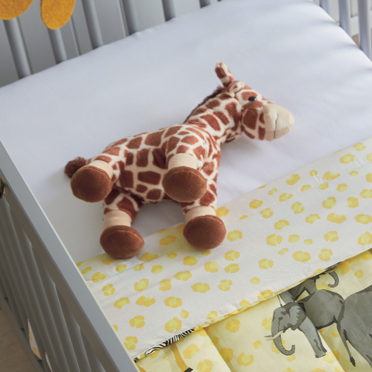 Giraffe Soft Toy laying down in cot
