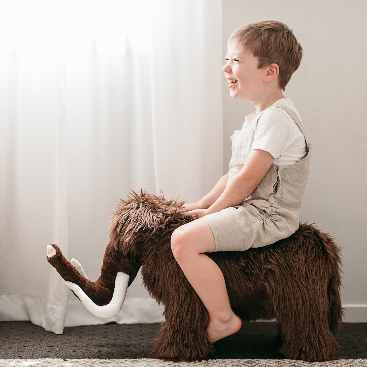 Lifestyle shot of child sitting on Mammoth Standing Animal