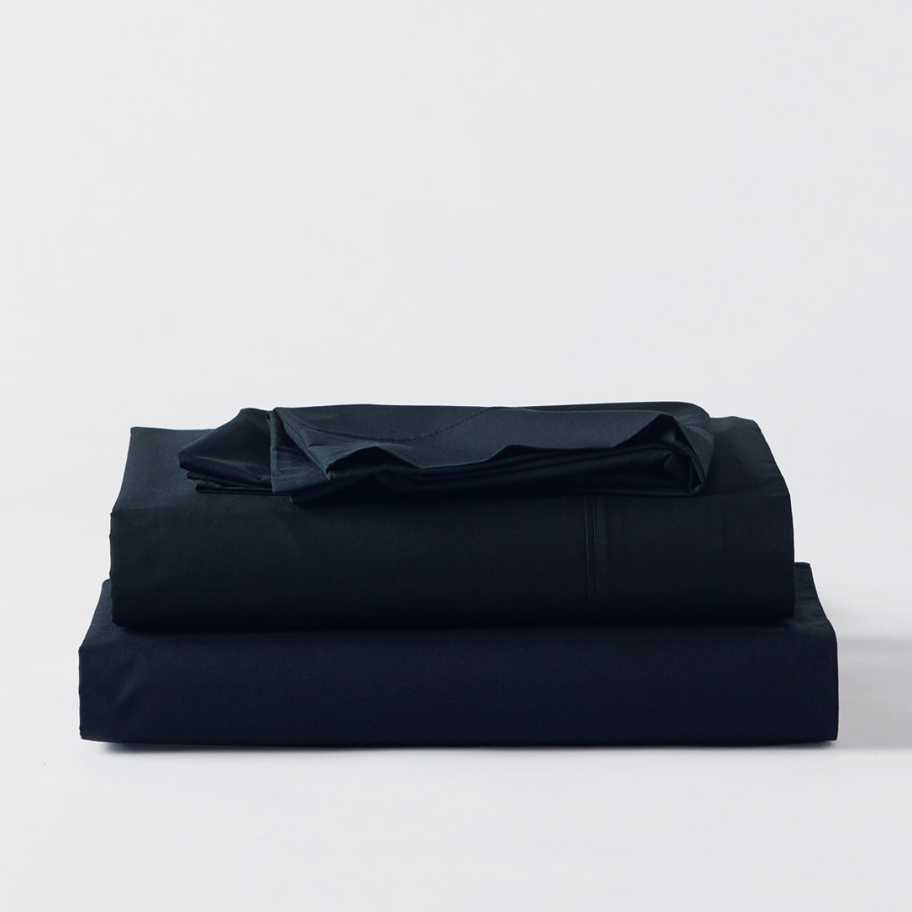 Premium Percale Black Sheets folded up on floor