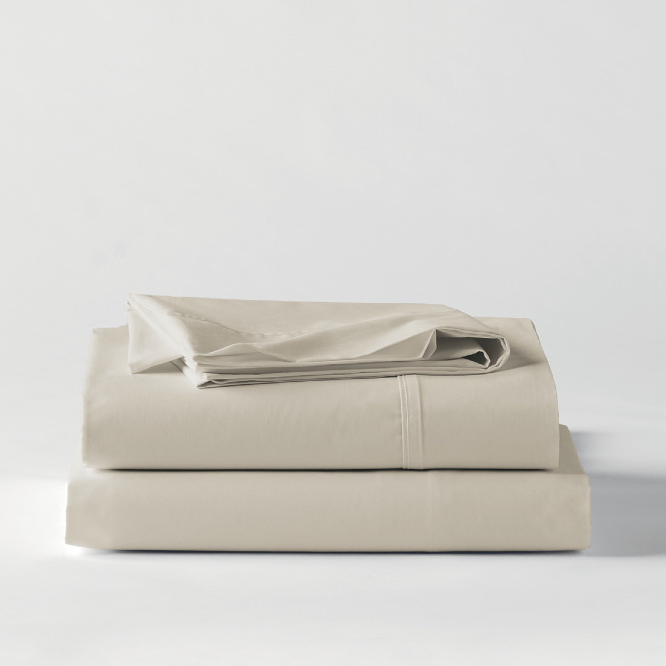 Premium Percale Oyster Sheets folded up on floor