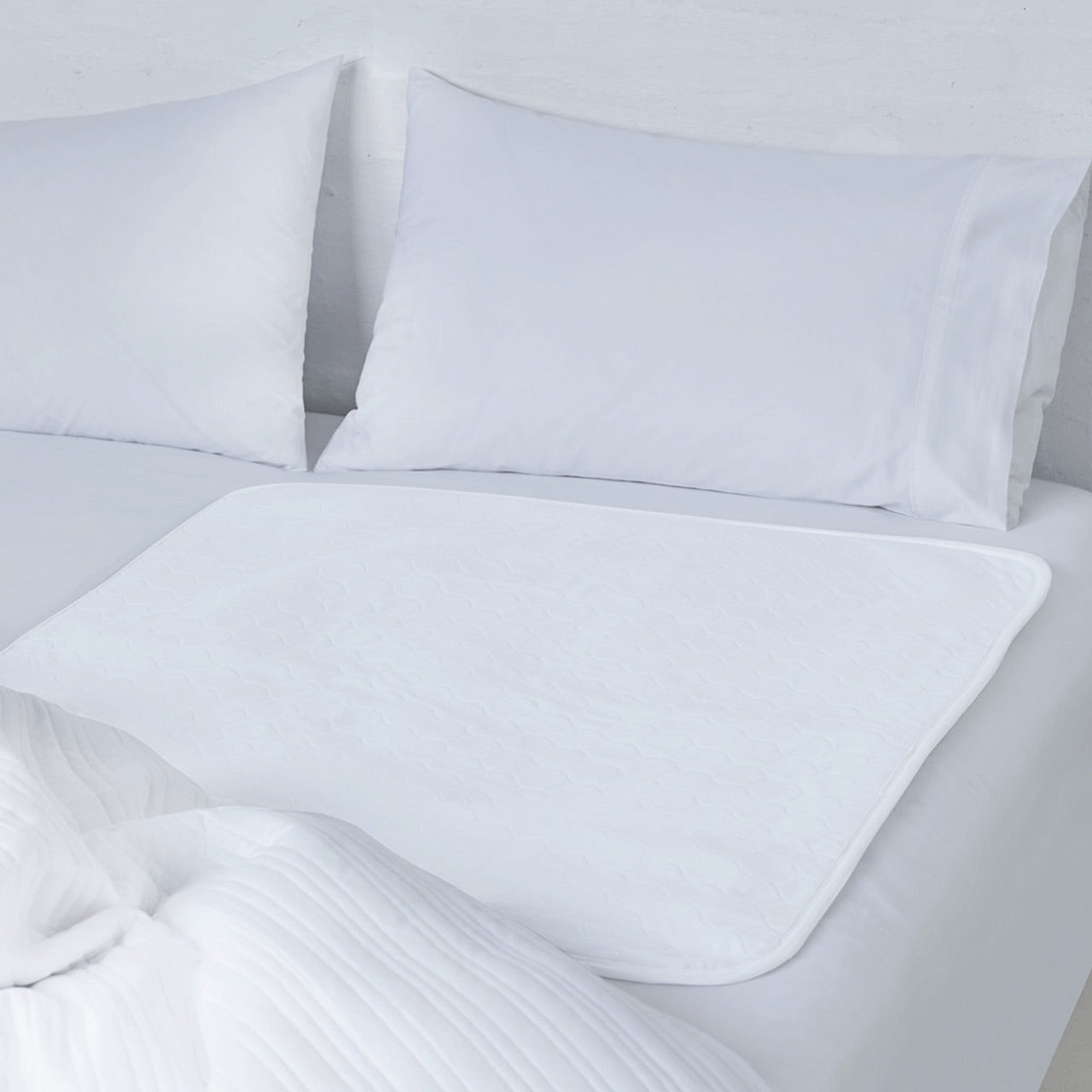 Sleep Easy Bed Mat on bed with pillows and a quilt