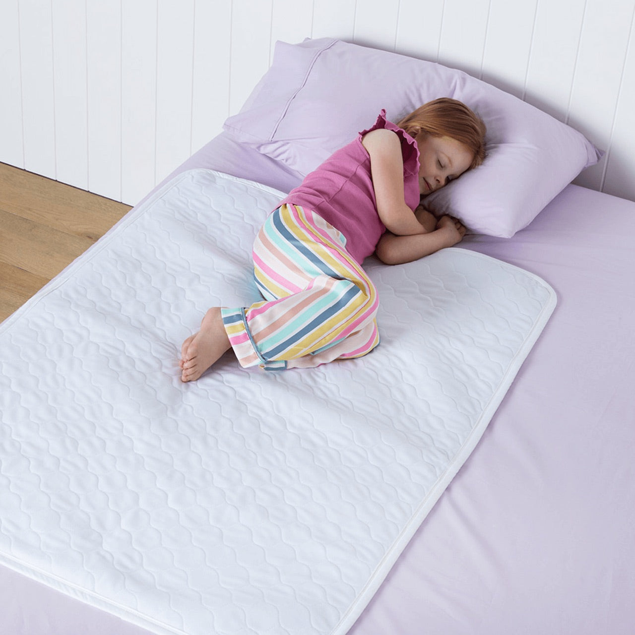 Child sleeping on bed with the Sleep Easy Bed Mat