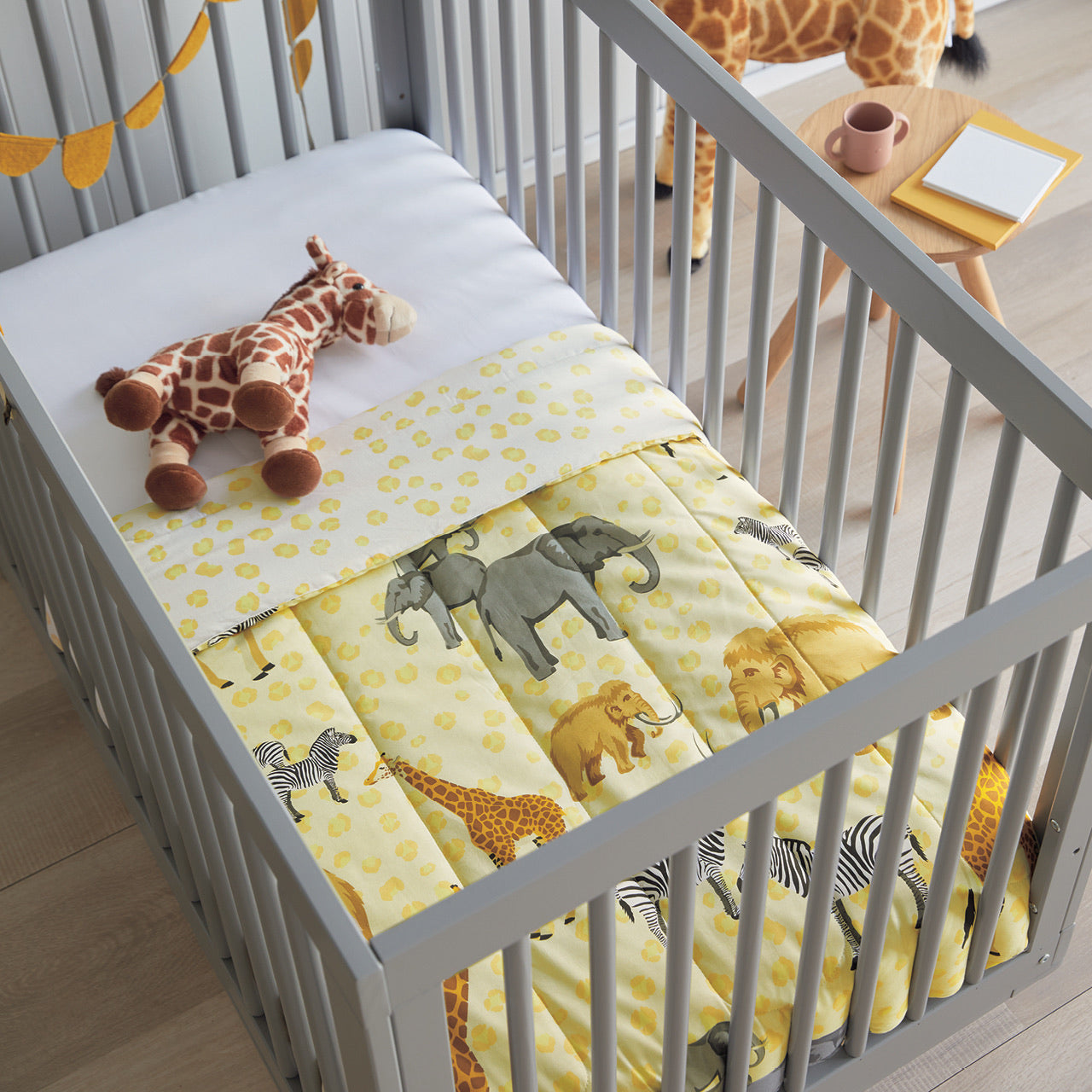 Taronga Cot Comforter in cot with toys