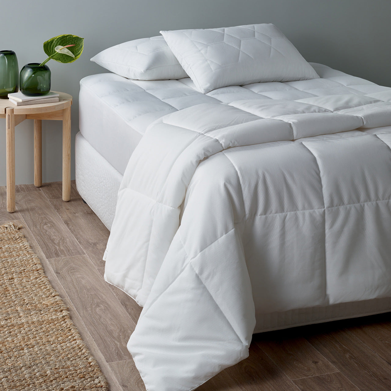 Corner view of Thermal Balancing Quilt on bed with matching pillow protector and mattress protector