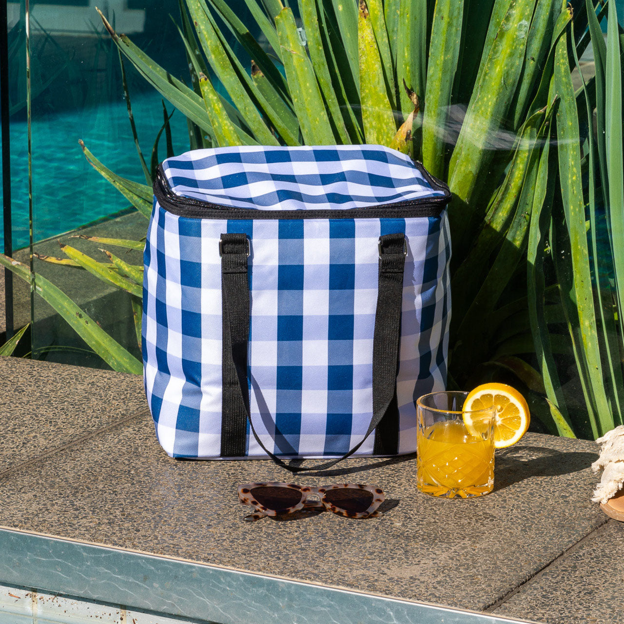 Lifestyle shot of Trinity Cooler Bag next to pool with drink and sunglasses