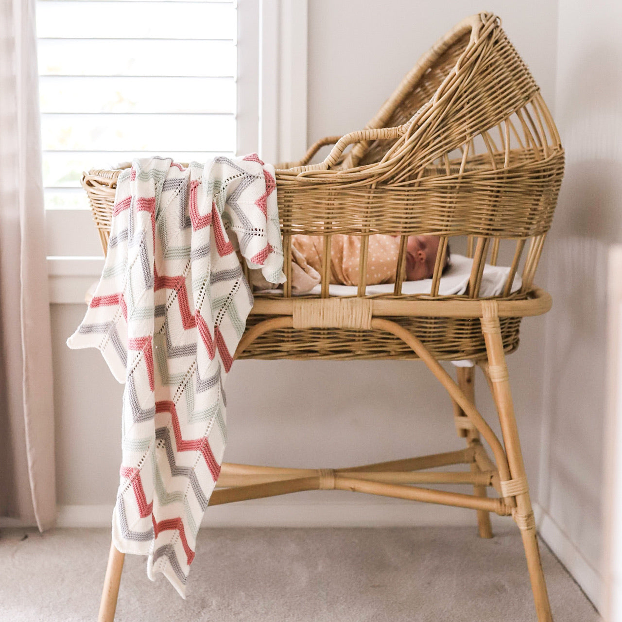 Lifestyle shot of Utopia Baby Blanket hanging over cot