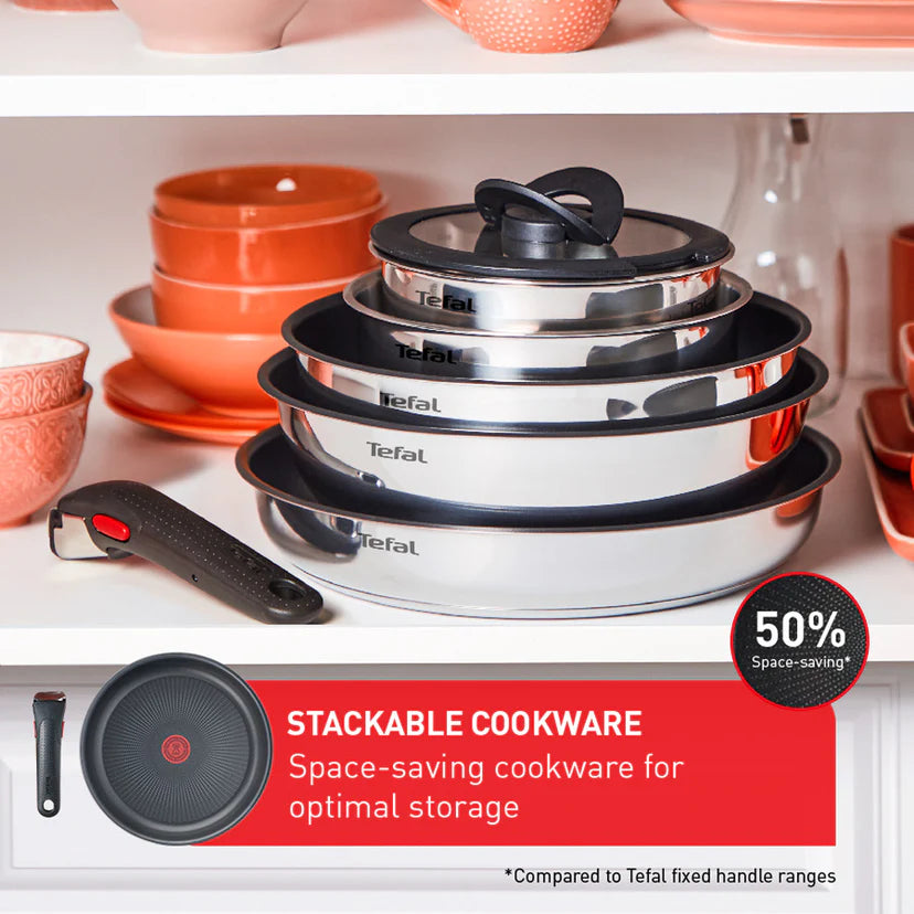 Stackable cookware set with Tefal branding on a kitchen shelf with orange bowls.