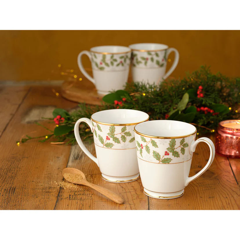 Set of Christmas-themed mugs on a wooden table with holly design