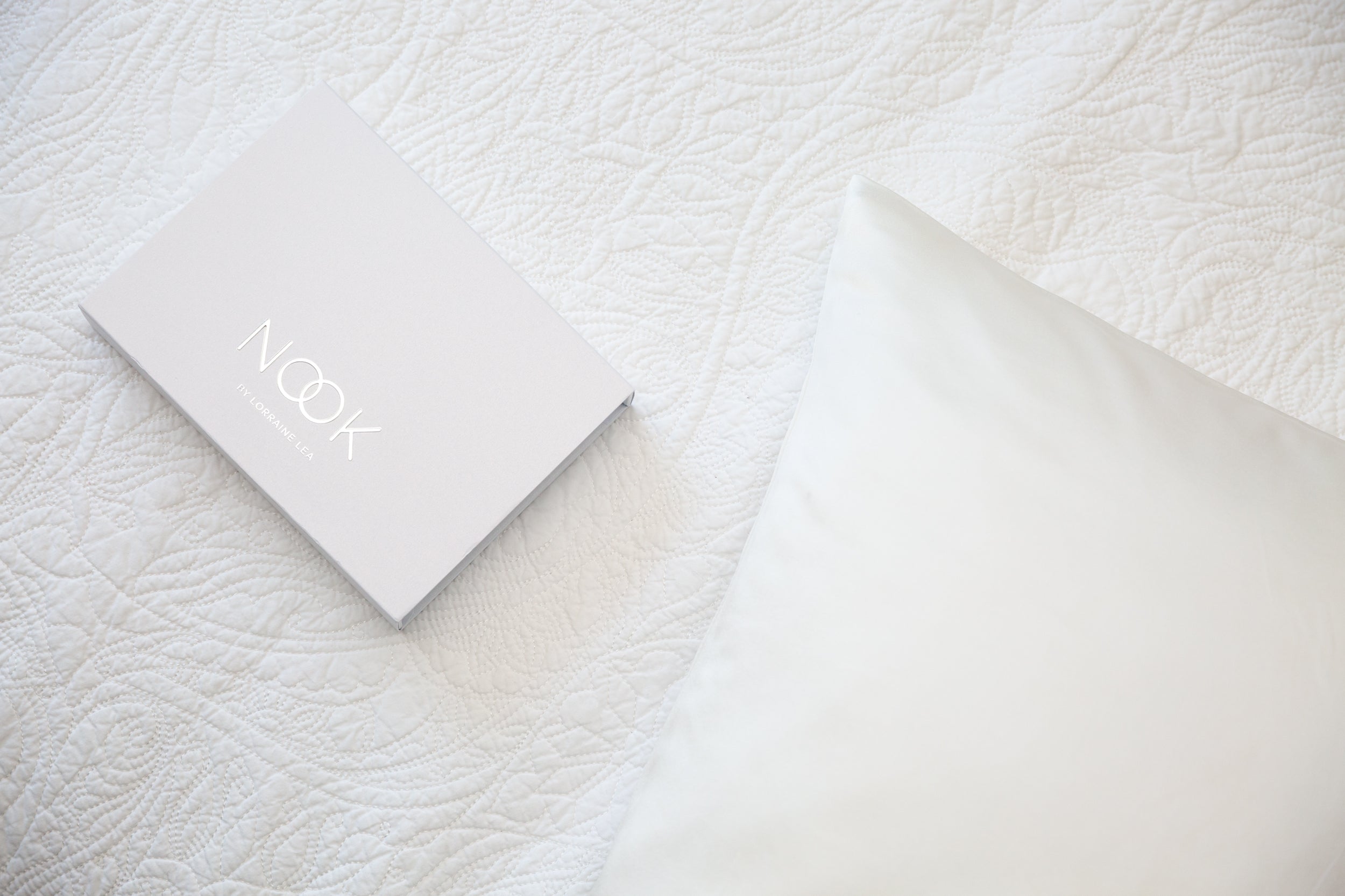 White pillow and envelope on a textured white surface