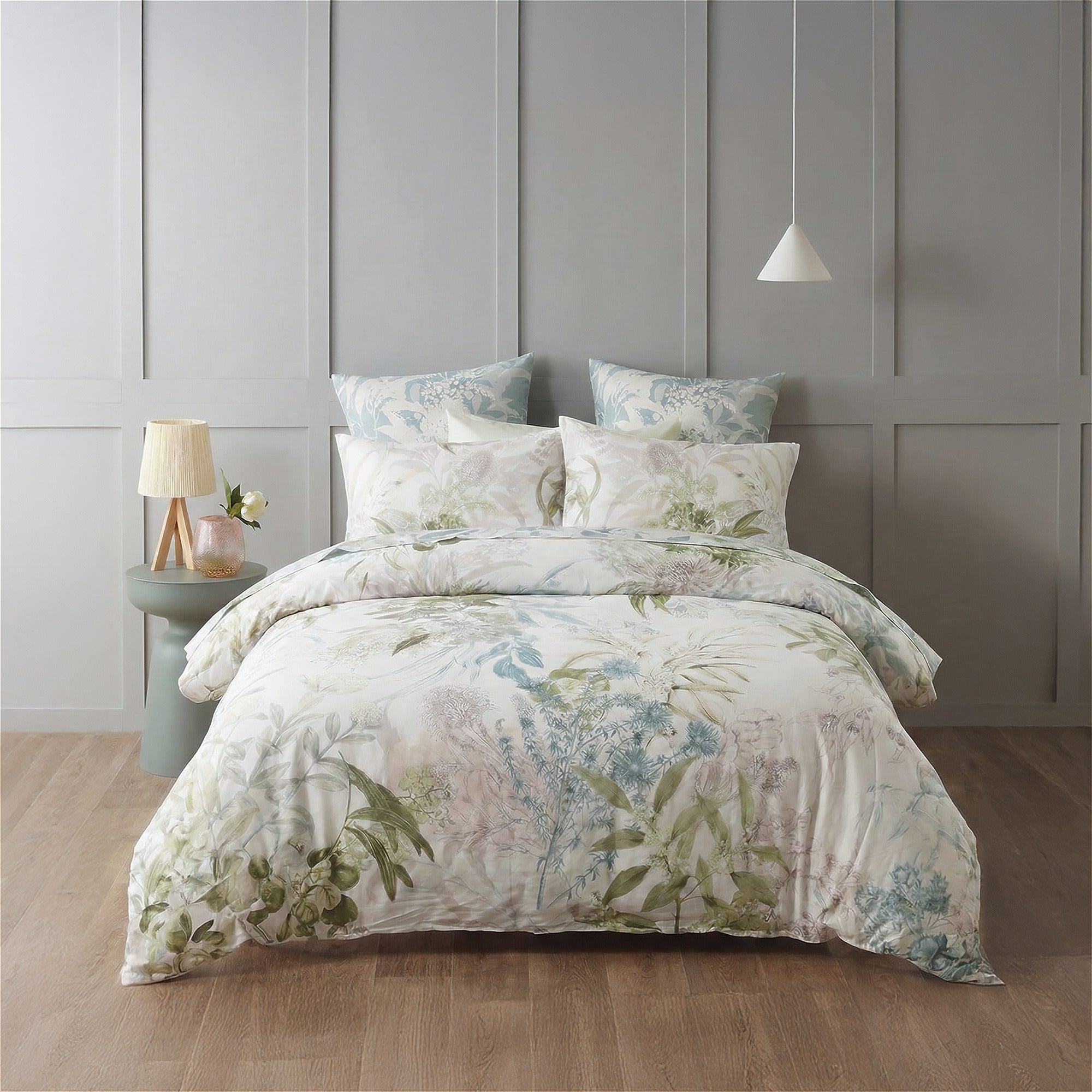 Floral bedding set on a bed in a bedroom with a gray paneled wall.