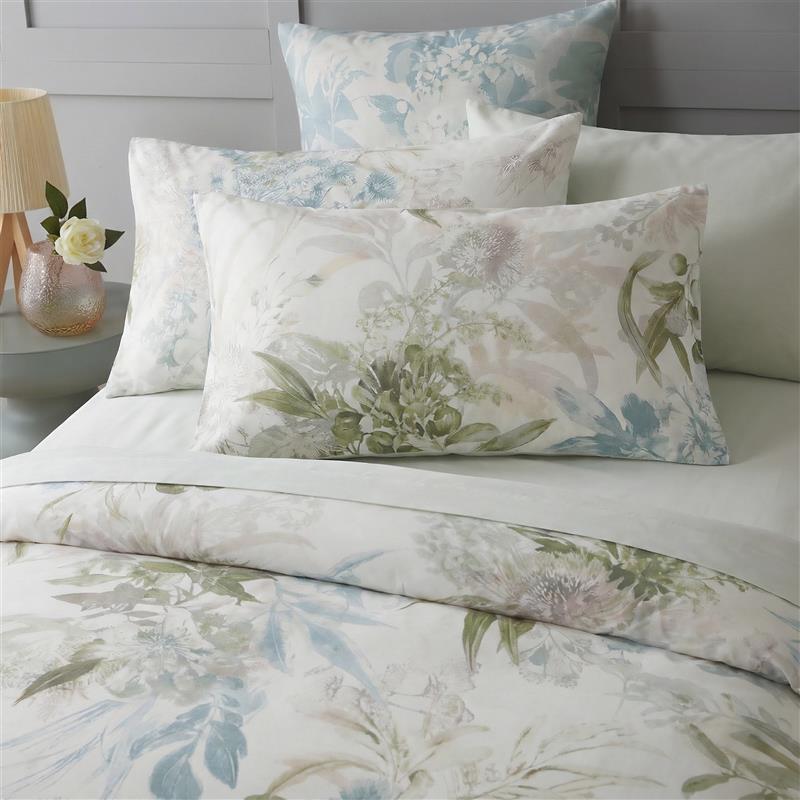 Floral patterned bedding set on a bed with a lamp and vase in the background.